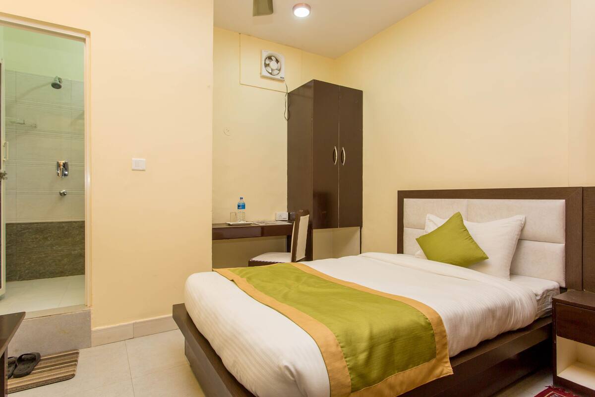 Une chambre d’hôtel comprenant un lit, un bureau, une armoire et un espace douche.