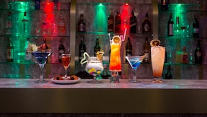 A bar with various colorful cocktails and bottles of liquor in the background.