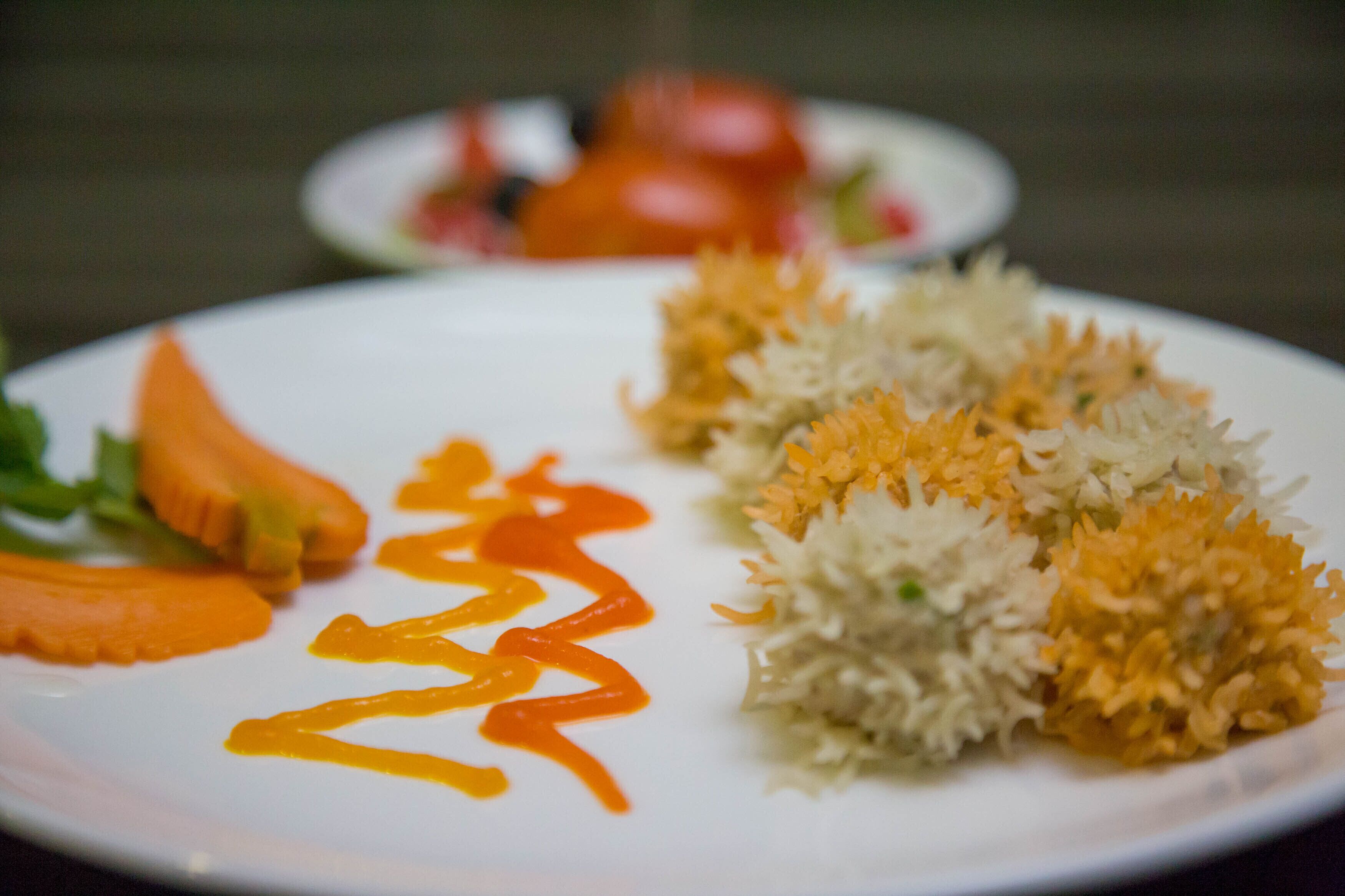 A plate with rice, carrots, and a sauce.