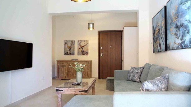 A living room with a sofa, a coffee table, a TV, and artwork on the wall. - Best House Anakreontos (Nikaia-Agios Ioannis Rentis)