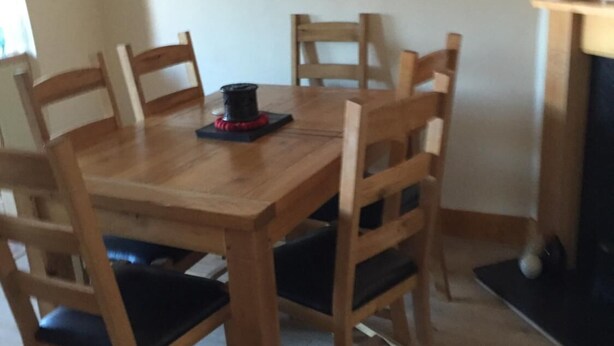 A wooden dining table with six chairs, a black object on the table, and a fireplace in the background. - Sturry House (Canterbury)