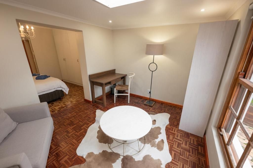 A compact room with a bed, a round table, a sofa, and a lamp.