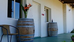 A building with two large wooden barrels, a chair, and a door with a sign. - Saxenburg Wine Farm (Cape Town)