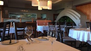 A restaurant interior with tables set for dining, overhead lighting, and a wall sign reading "Cattle Bar". - Saxenburg Wine Farm (Cape Town)