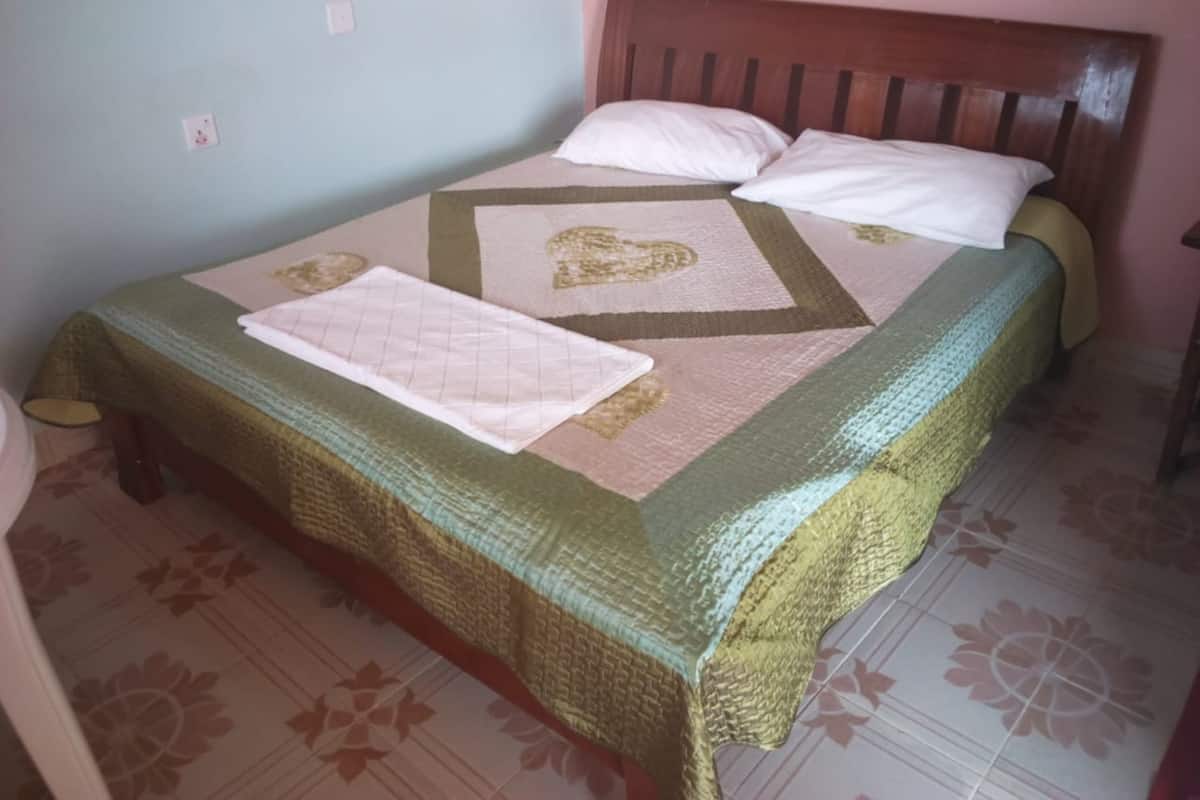 A bed with a patterned bedspread, pillows, and a quilt.
