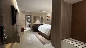 A modern hotel room with a large bed, a flat-screen TV mounted on the wall, and a walk-in closet. - Sixty Three Hotel (Riyadh)