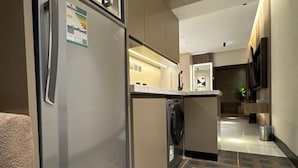 A modern kitchen with a stainless steel refrigerator, a built-in oven, and a microwave. The floor has a geometric tile pattern. - Sixty Three Hotel (Riyadh)