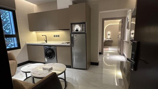 A modern kitchen with built-in appliances, a dining area with a marble table, and a hallway leading to another room. - Sixty Three Hotel (Riyadh)