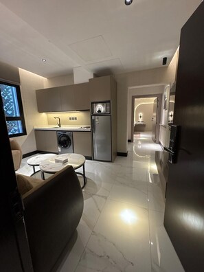 Una cocina moderna con electrodomésticos integrados, un comedor con mesa de mármol y un pasillo que conduce a otra habitación.