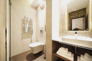 A modern bathroom with a toilet, a towel rack, and a vanity with a mirror. - NV Luxury Suites & Spa (Belgrade)