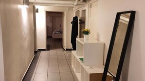 A narrow hallway with tiled flooring, white walls, and a white bench with a mirror leaning against the wall. - Thorsgade 1A (Odense)