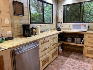 A kitchen with wooden cabinets, a coffee maker, a microwave, and a dishwasher. - Uvita Oasis Retreat - Deluxe Villa (Uvita)