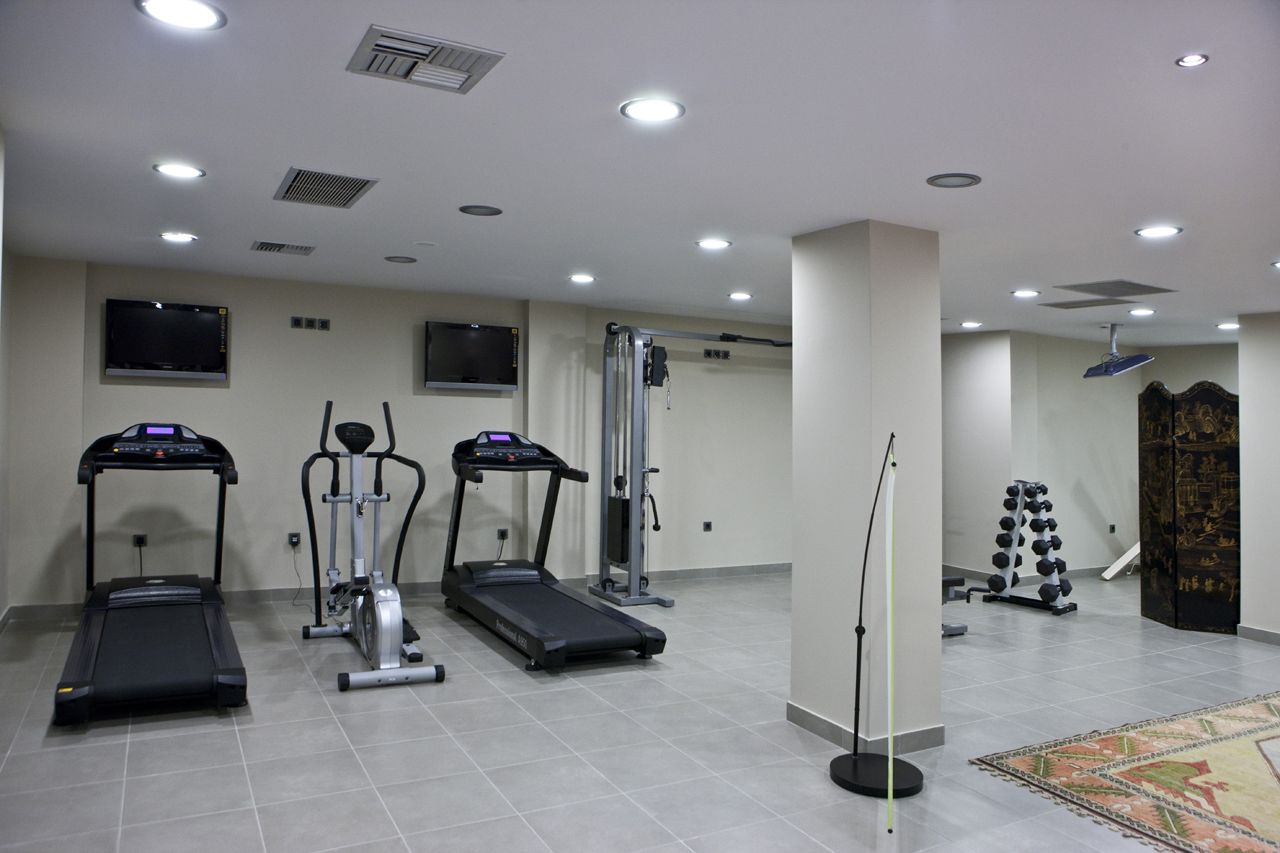 A fitness center with treadmills, an elliptical, a weight bench, and a rack of dumbbells.