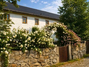 Un edificio bianco con muro in pietra e cancello in legno.