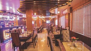 A restaurant with a bar area, wooden ceiling, and a TV screen.