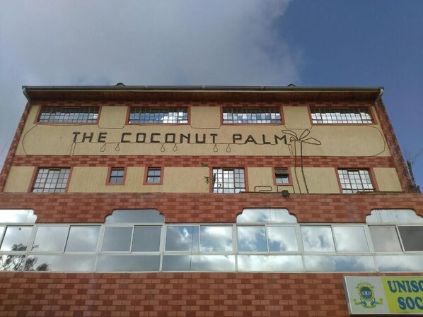 Un bâtiment portant l’enseigne « The Coconut Palm » et arborant le logo de « UNISO SOC ».