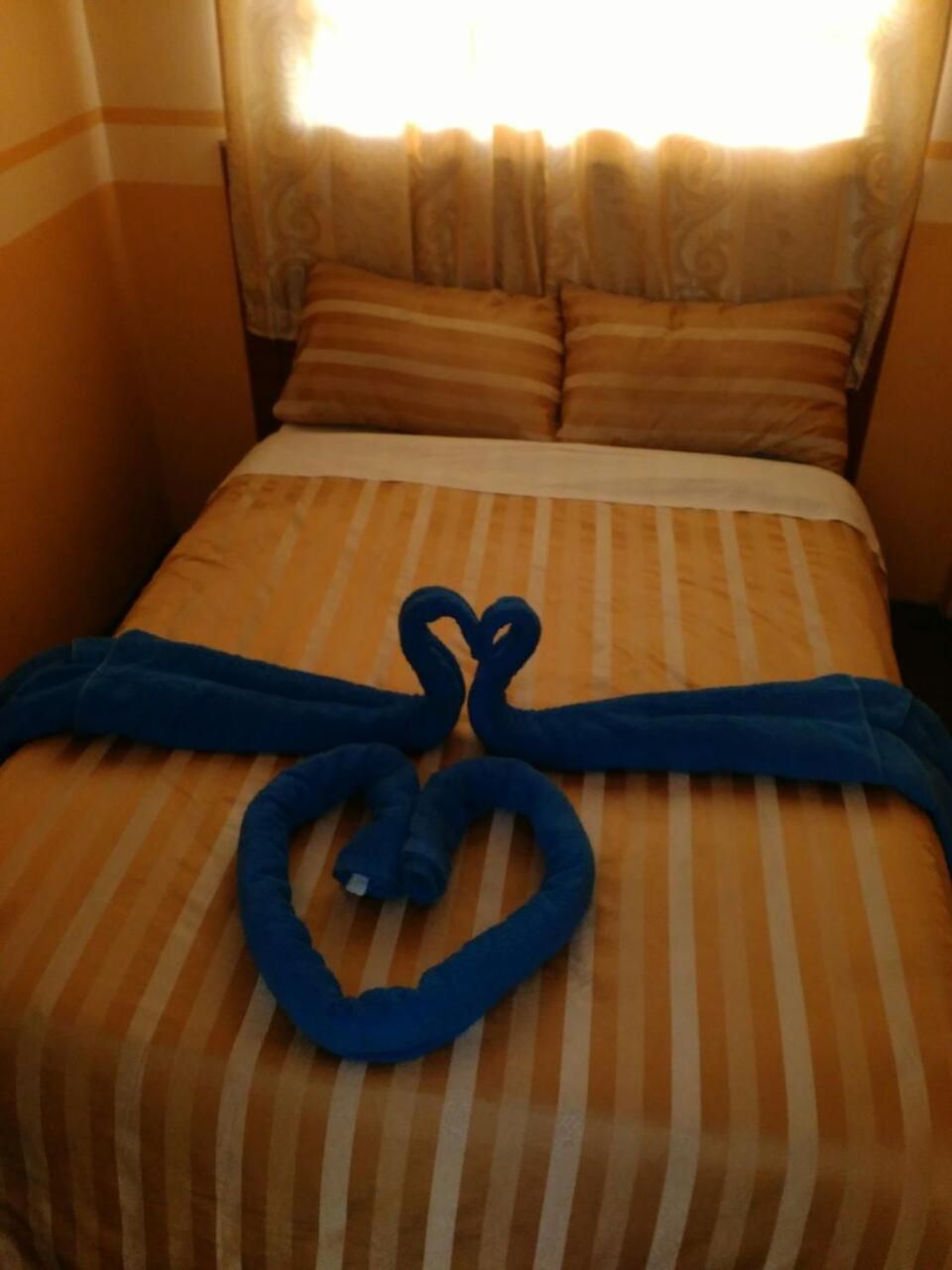 A bed with striped bedding and two blue towels arranged on it.