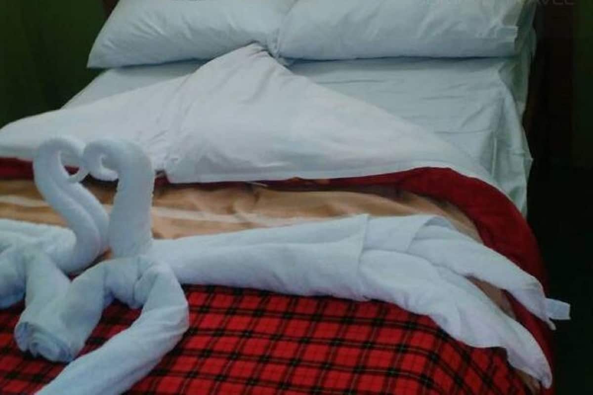 Ein Bett mit einer rot-schwarz karierten Tagesdecke und weißen Kissen.