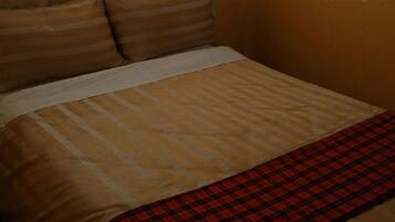 A bed with a striped bedspread and a plaid blanket.