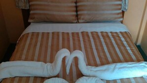 Una cama con ropa de cama a rayas, dos almohadas y toallas dispuestas en forma de corazón.