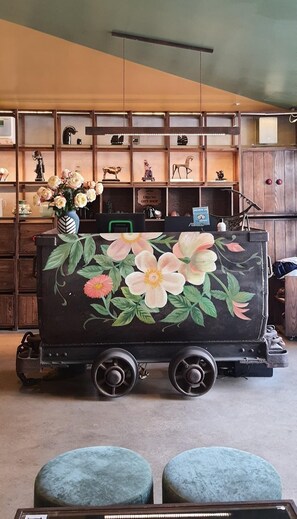 Un vagón de tren antiguo con motivos florales, ubicado en una habitación con estanterías de madera y varios objetos decorativos.