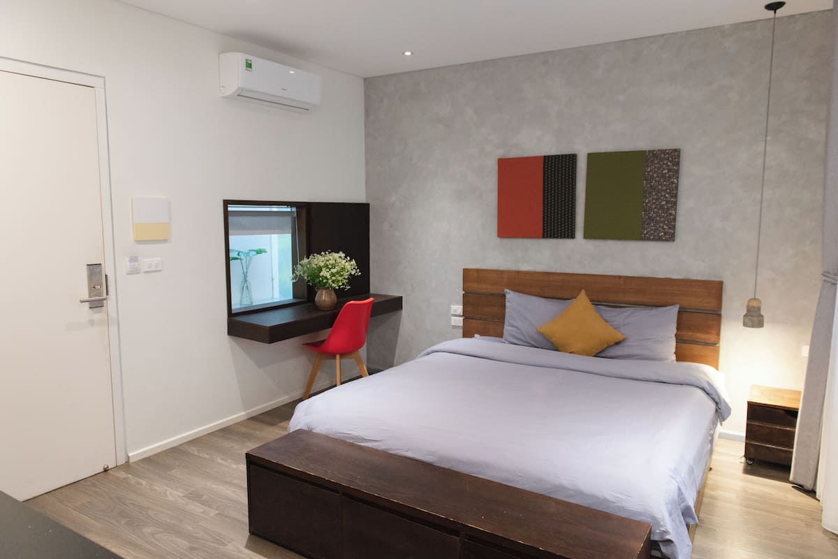 A modern bedroom with a large bed, a desk, and a chair.