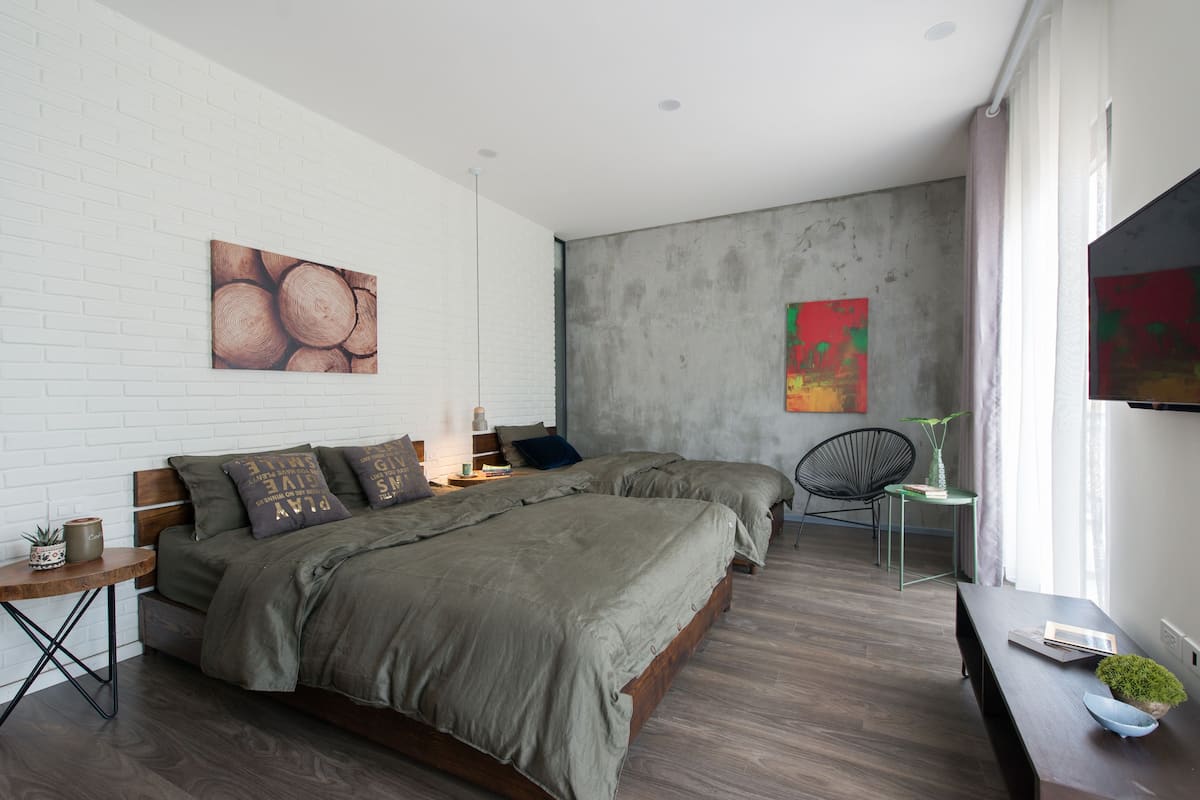 A modern bedroom with a large bed, a small table, and a chair.