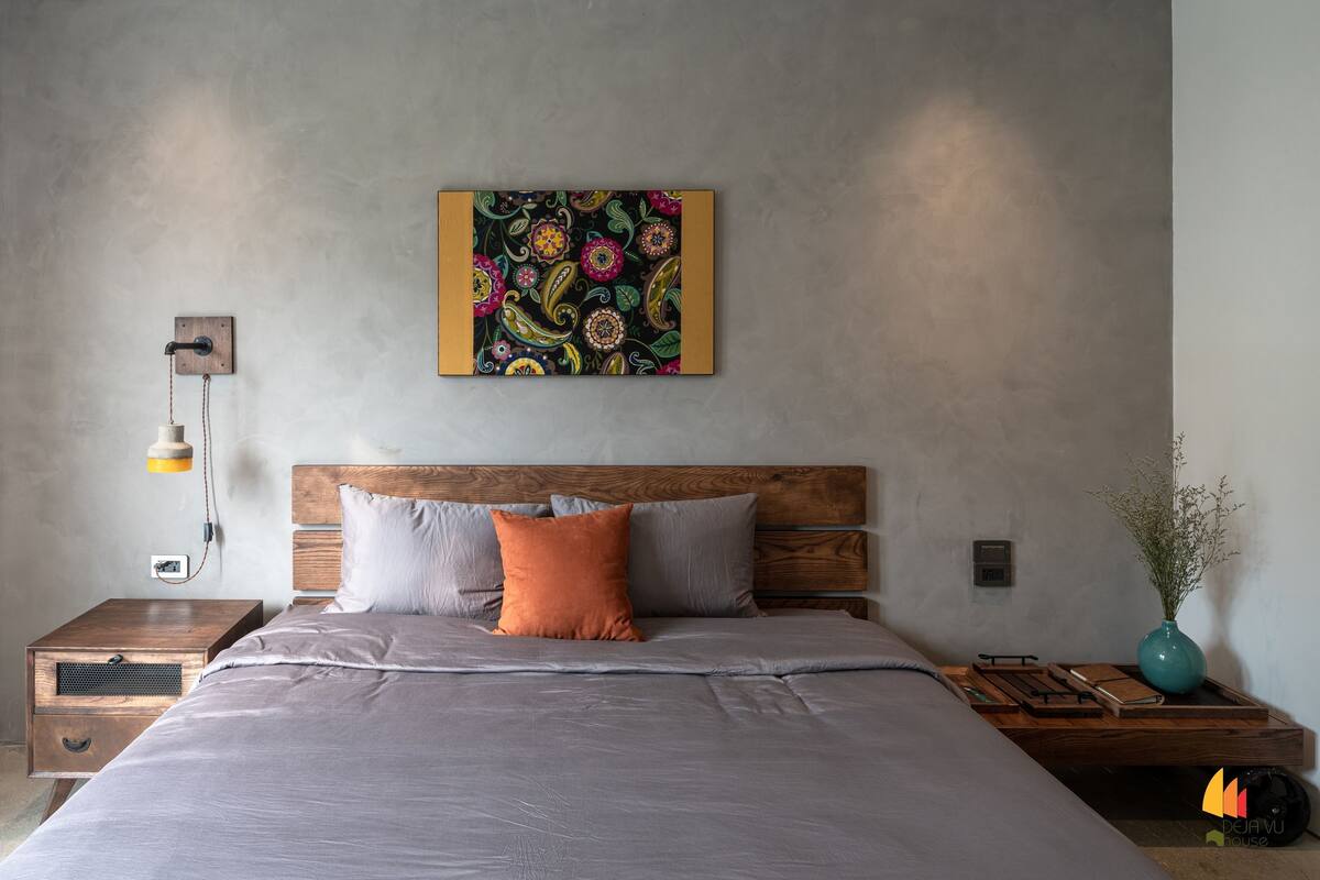 A modern bedroom with a large bed, wooden headboard, and a colorful abstract painting above it.