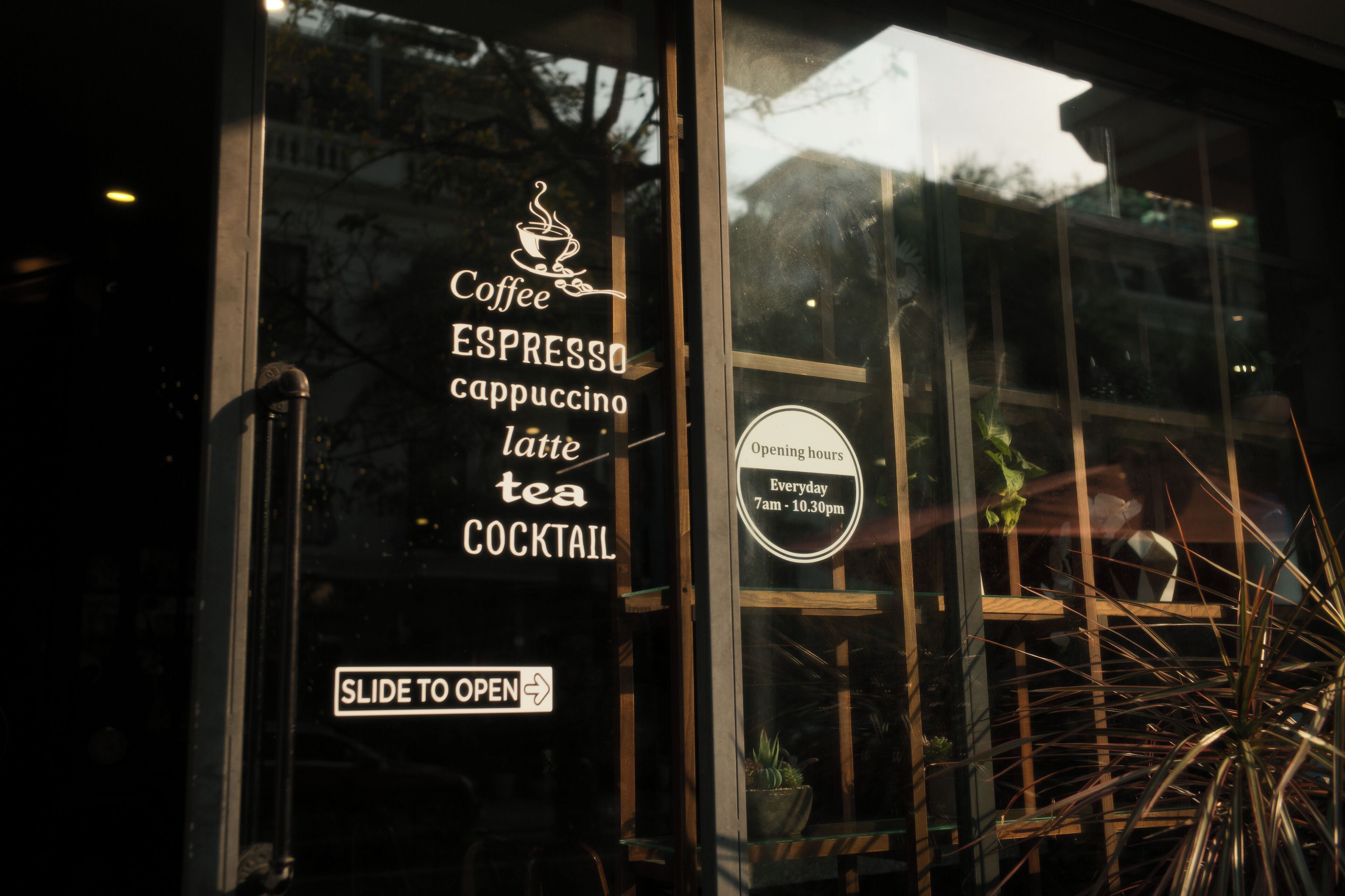 A coffee shop sign with offerings like espresso, cappuccino, latte, and tea, and a slide to open sign.