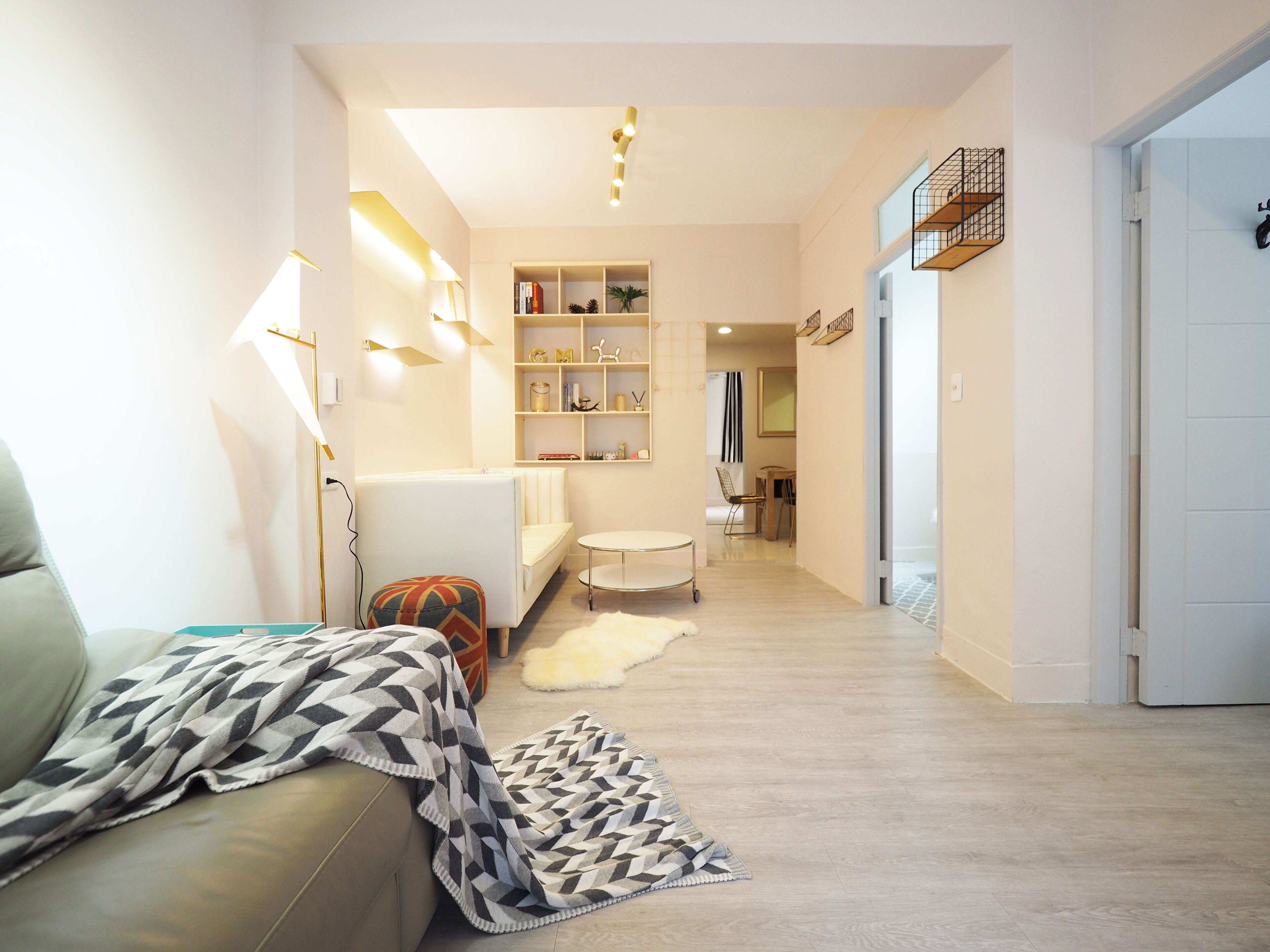 A modern living room with a sofa, a patterned throw, a small round table, and a bookshelf.
