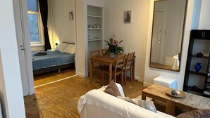 Ein gemütliches Wohnzimmer mit einer Couch, einem Holzesstisch und einer kleinen Küchenzeile.