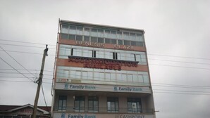 A multi-story building with the signage 'GENESIS PLAZA' and 'ACCOMMODATION AVAILABLE'. It has multiple 'Family Bank' and 'CASHPOINT' signs. - Ideal Hotel (Kiriaini)