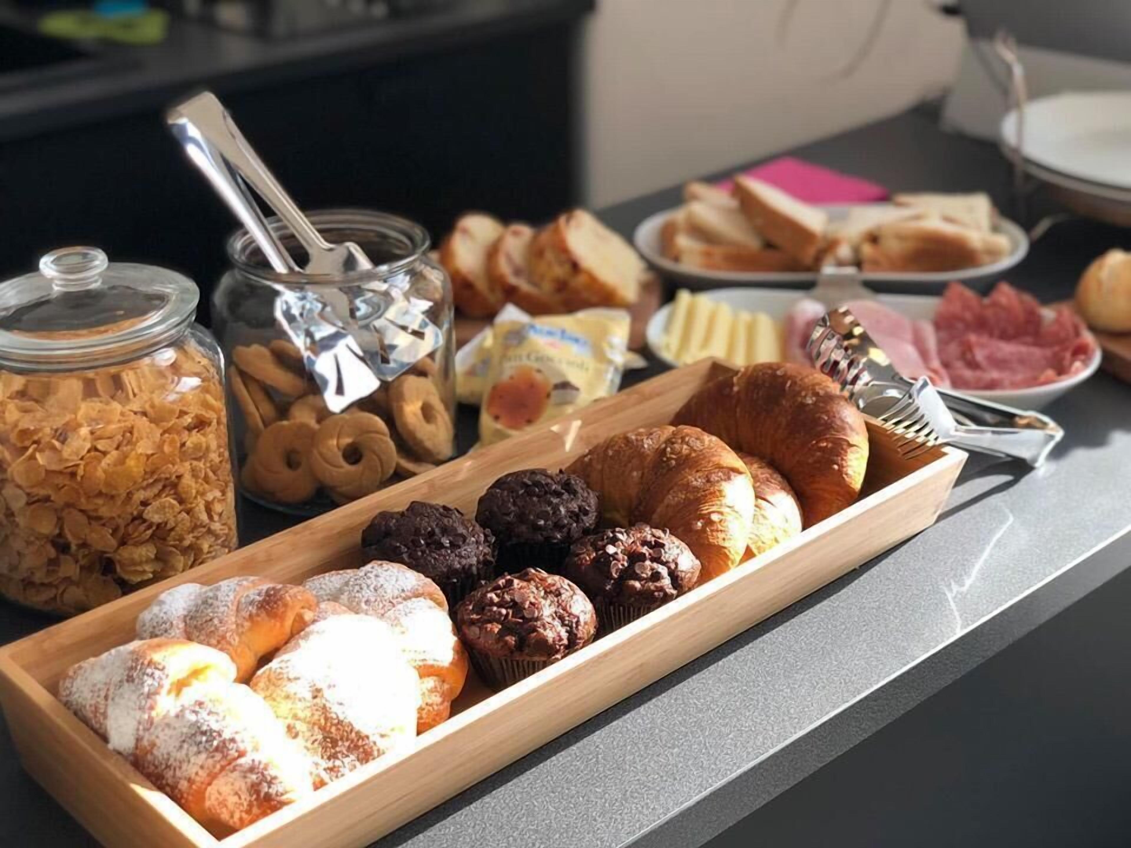 A breakfast buffet with pastries, bread, and condiments.