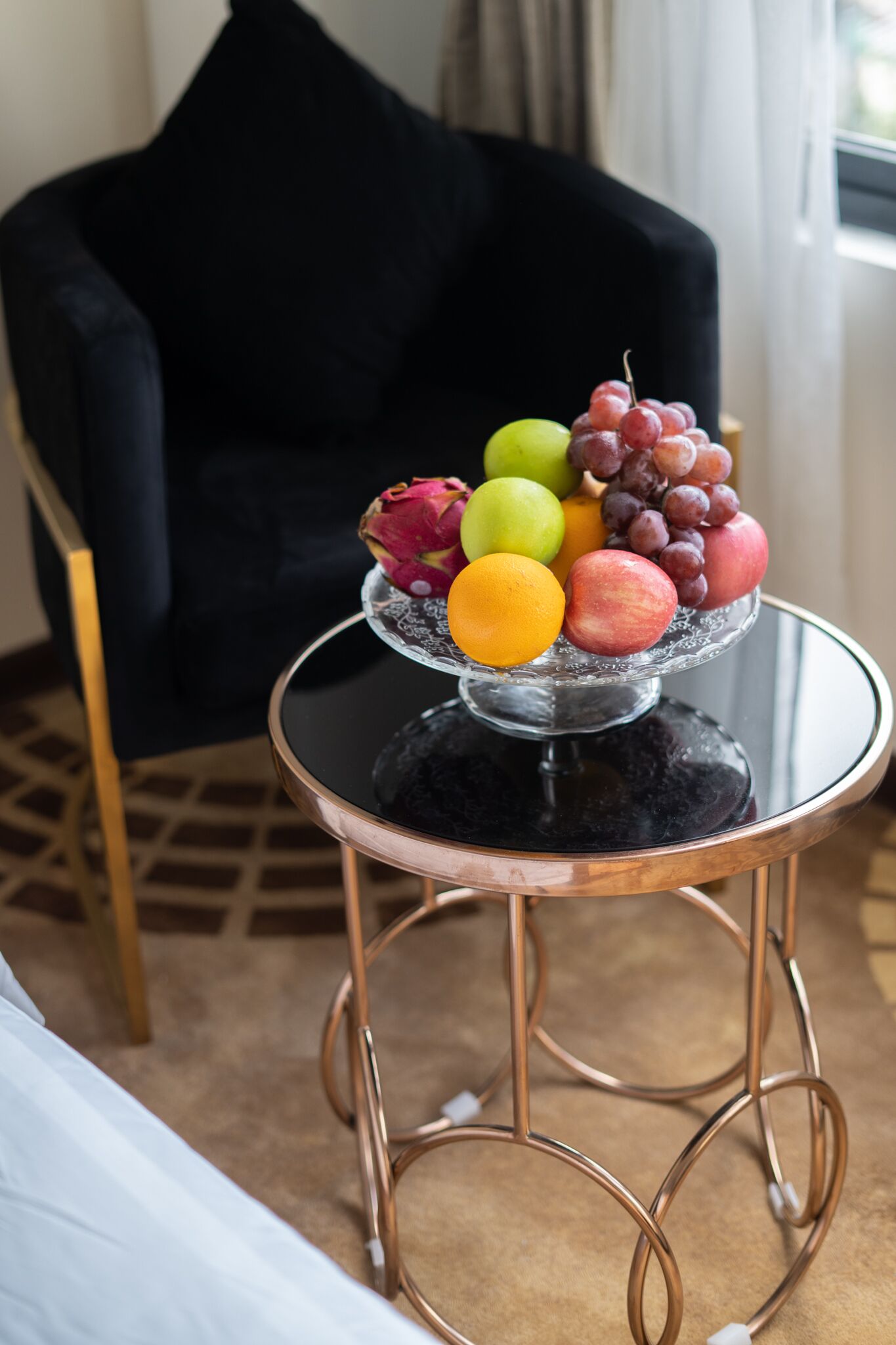 A glass table with a fruit arrangement in a hotel room.