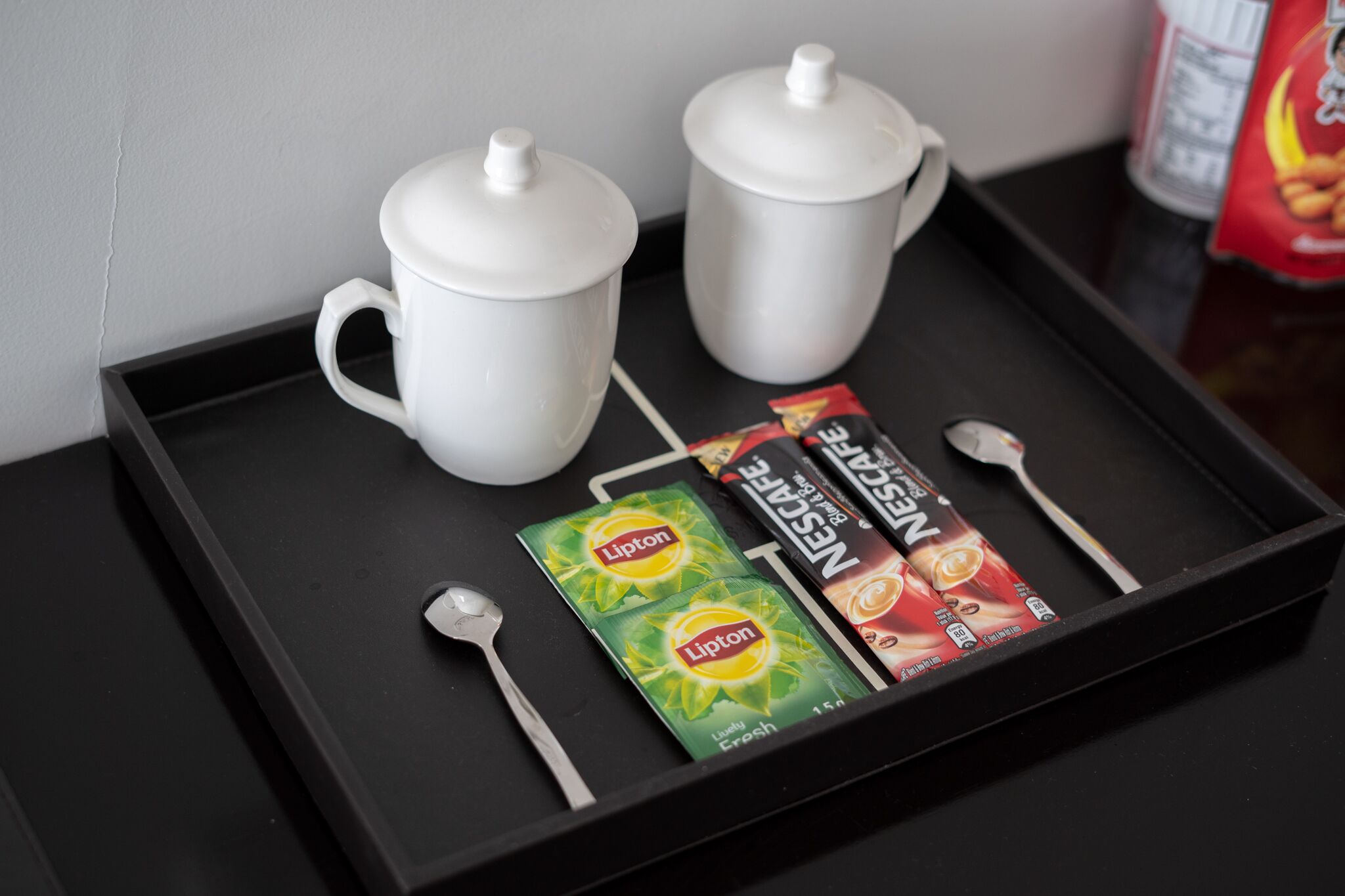 A tray with two white mugs, two Lipton tea packets, and two Nestle tea packets.