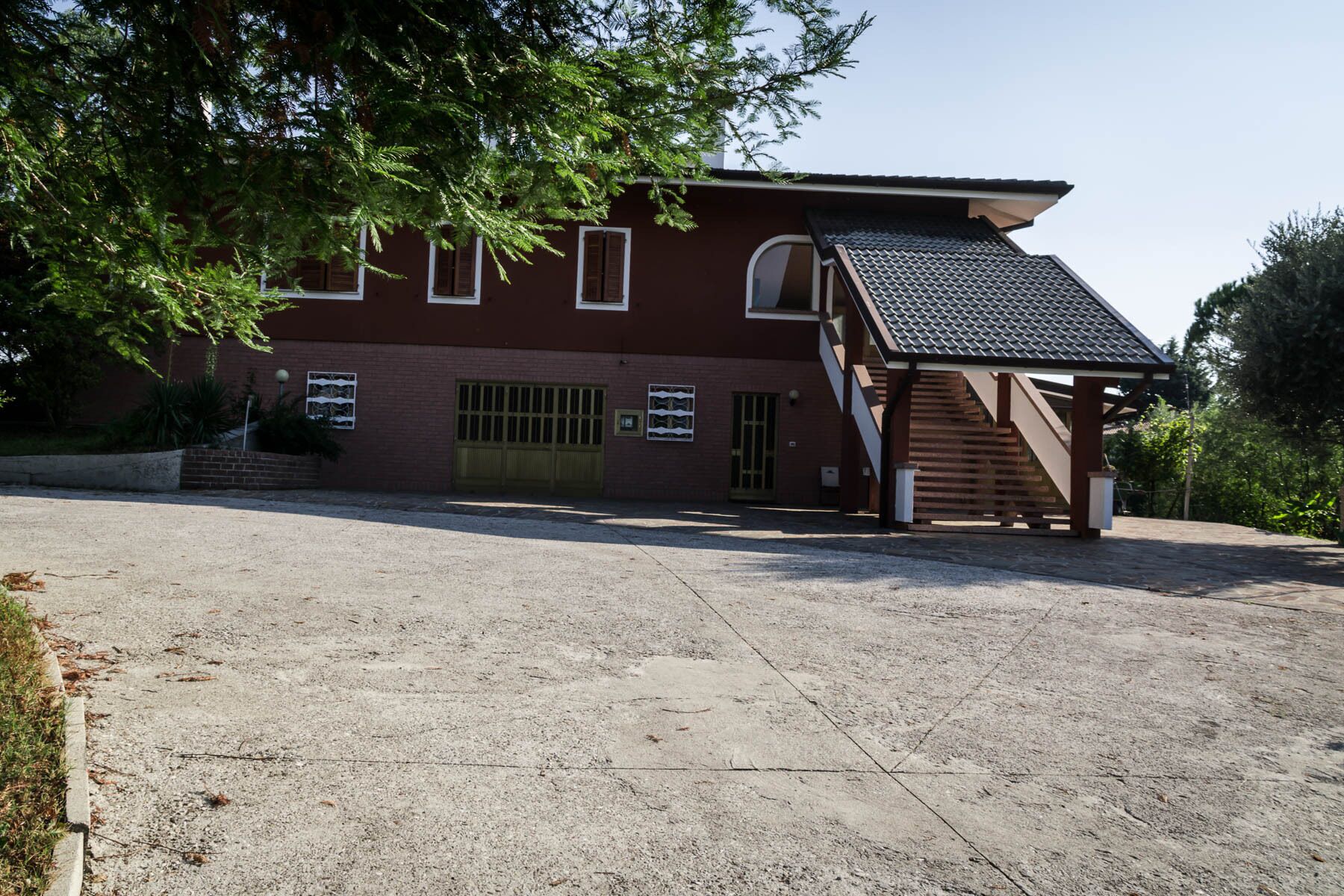 A building with a brick facade, a covered staircase, and a gravel driveway.