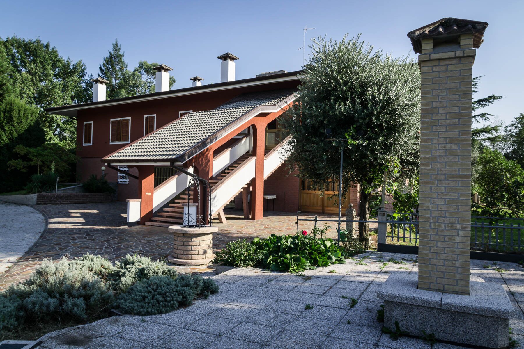 Et toetagers hus med en trappe op til øvre etage, en murstens skorsten og en stenstolpe.