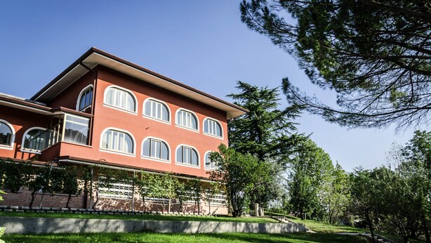 Un edificio de dos pisos con fachada roja y varios ventanales arqueados.