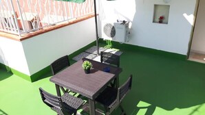 A patio with a table and chairs, a small potted plant, and a white air conditioning unit. - Casa Belvedere Suite (Barletta)