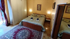 A bedroom with a bed, a nightstand, a wardrobe, and a chandelier. - Casa Belvedere Suite (Barletta)