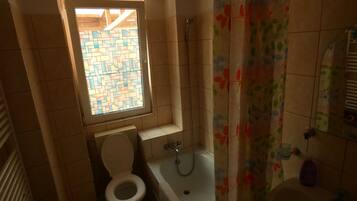 Un bagno piccolo con il water, una vasca da bagno e una finestra con un motivo a piastrelle geometriche.