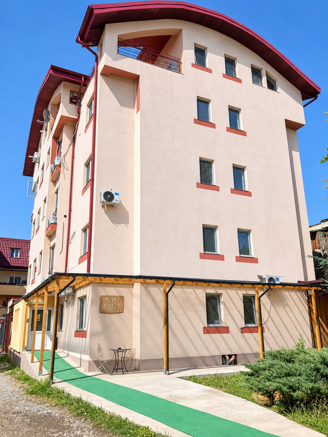Un hôtel à plusieurs étages doté de balcons, de climatiseurs et d’un hall d’entrée recouvert d’une moquette verte.