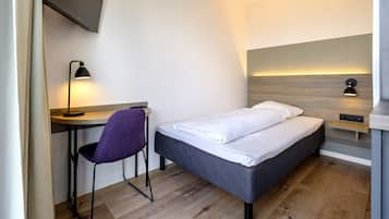Une chambre moderne comprenant un lit, un bureau, une chaise et deux lampes fixées au mur.