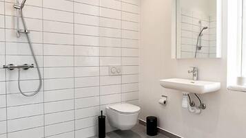 Un baño moderno con inodoro, lavamanos y ducha.
