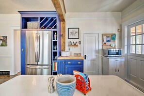 Una cocina moderna con un refrigerador de acero inoxidable, armarios azules, un microondas y una encimera blanca.