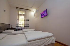 A hotel room with two single beds, a window with sheer curtains, an air conditioning unit, and a flat-screen TV mounted on the wall. - Mini Hotel Yerevan (Yerevan)