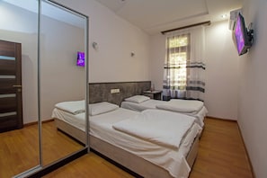 A hotel room with three beds, a large mirror, a TV, and a window with curtains. - Mini Hotel Yerevan (Yerevan)