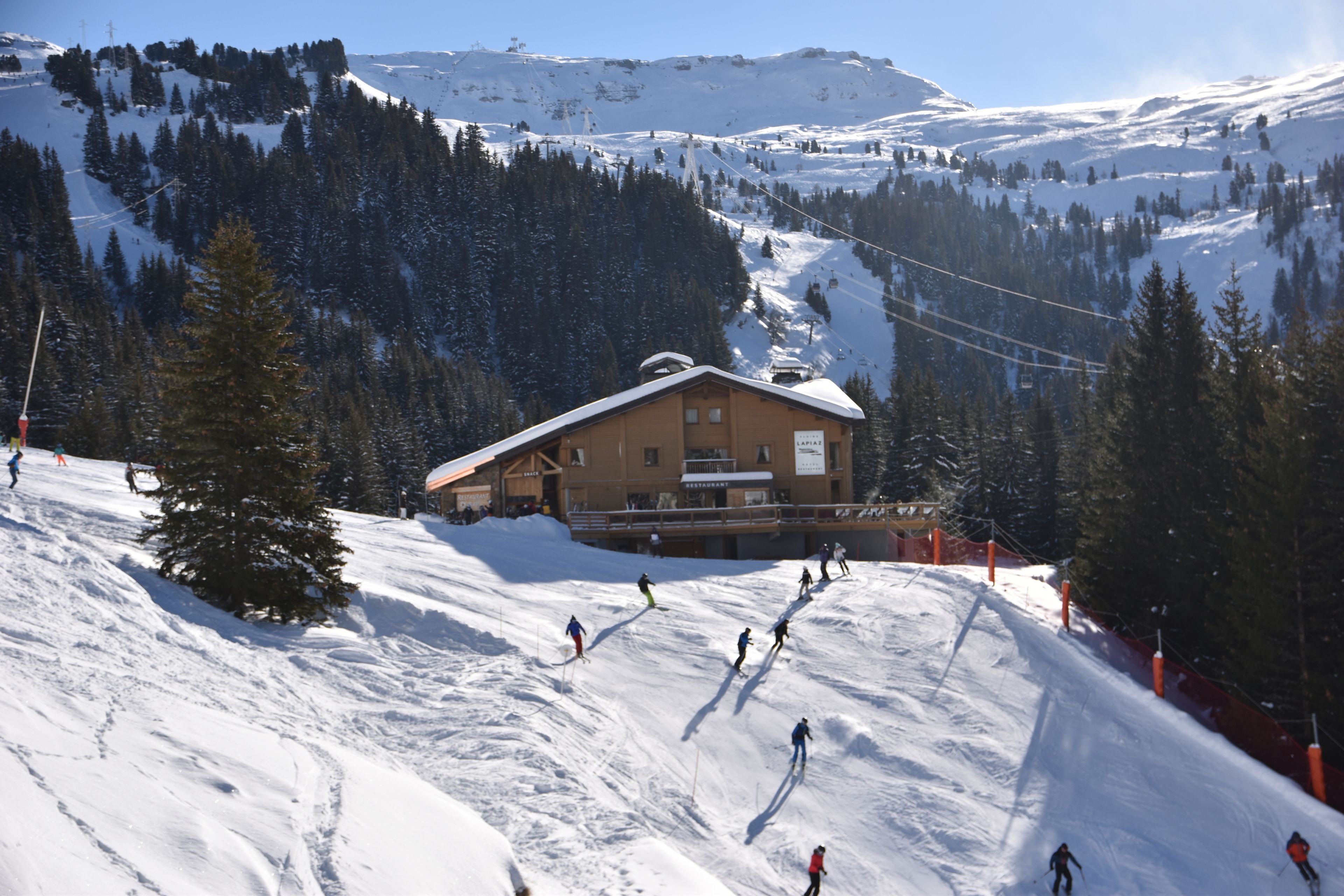 Une station de ski dotée d’un chalet, de pistes de ski et entourée d’une forêt.