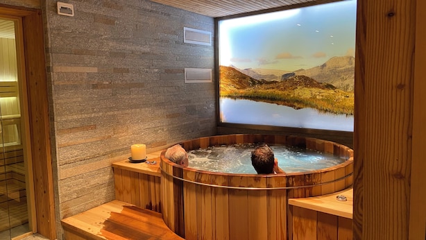 A wooden hot tub with a view of a mountainous landscape.