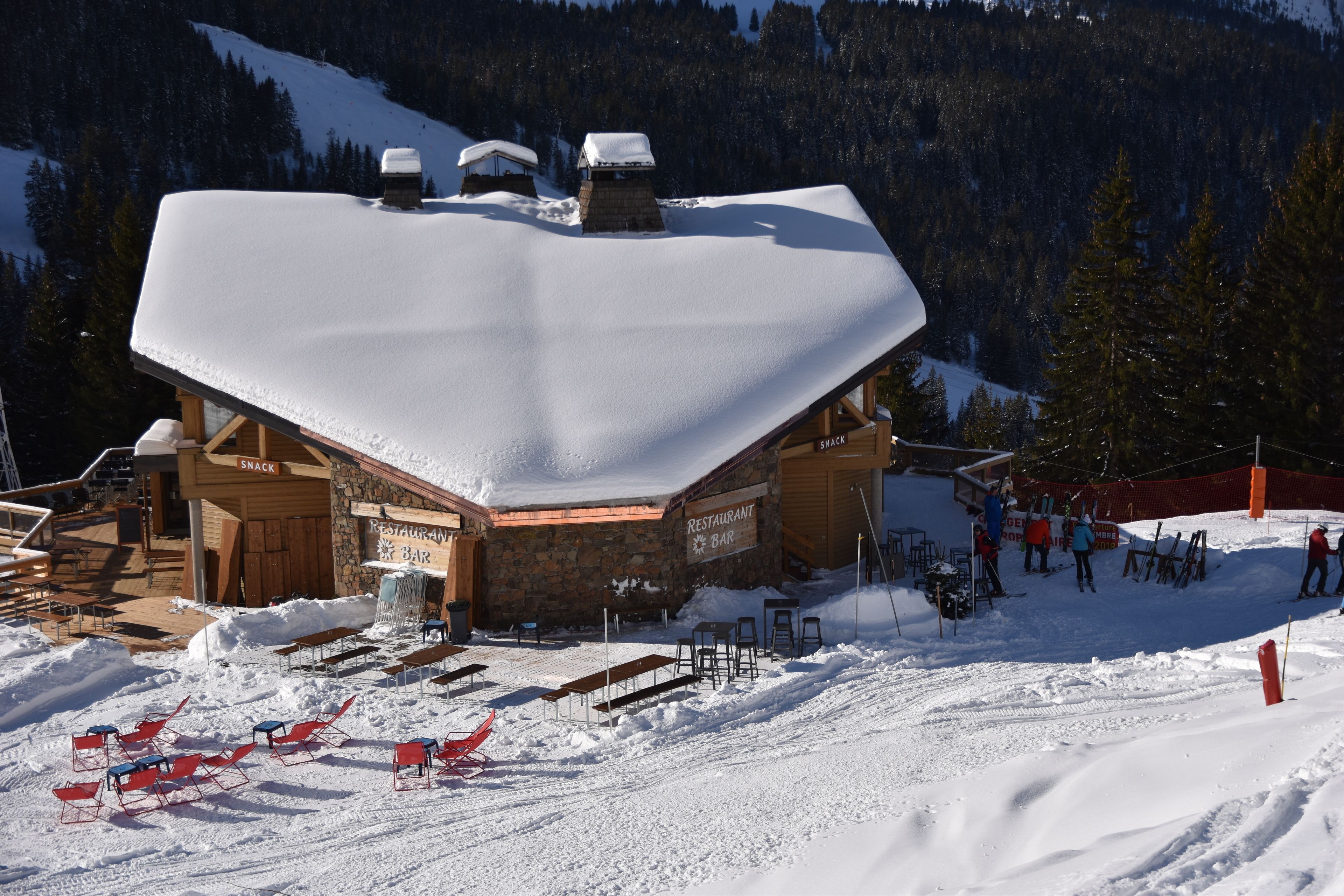 Un edificio imbiancato dalla neve con ristorante, bar e area salotto all'aperto.